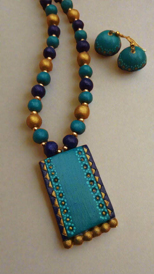 Turquoise and gold beaded necklace with matching earrings on a textured surface