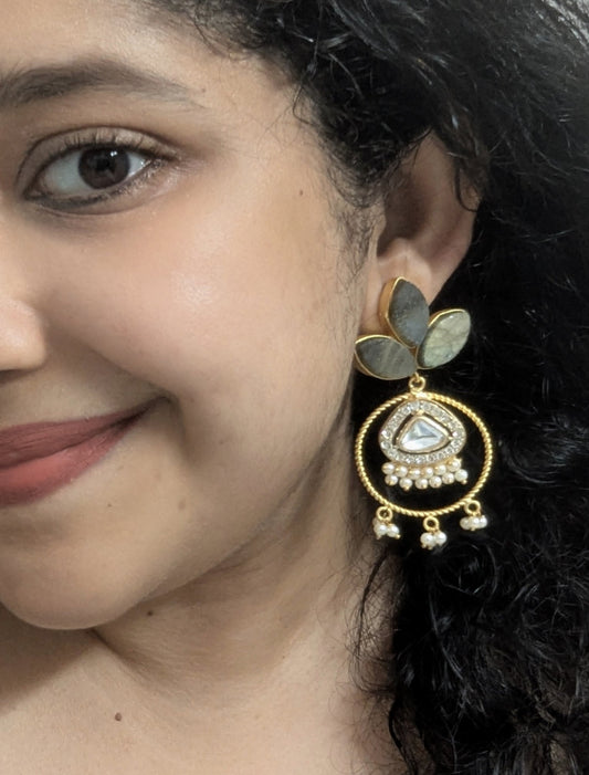 Close-up of a woman wearing a gold earring with green gemstones.