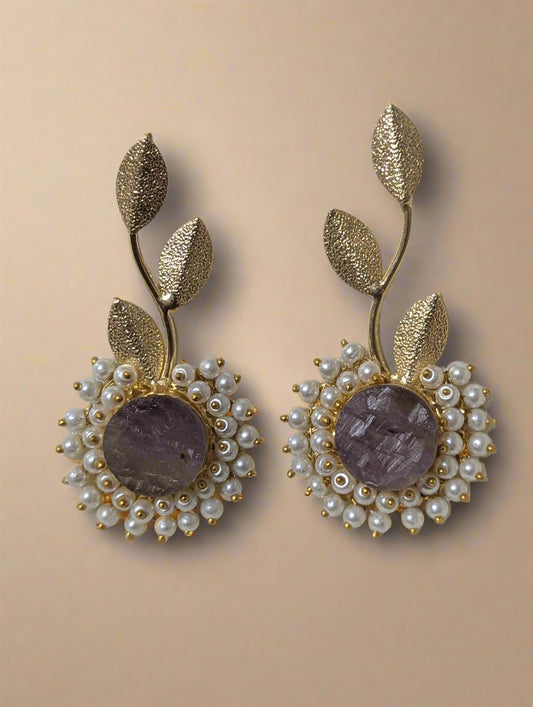 Pair of gold and pearl earrings on a light background