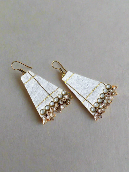Pair of white triangle earrings with pearl-like beads on a light fabric background